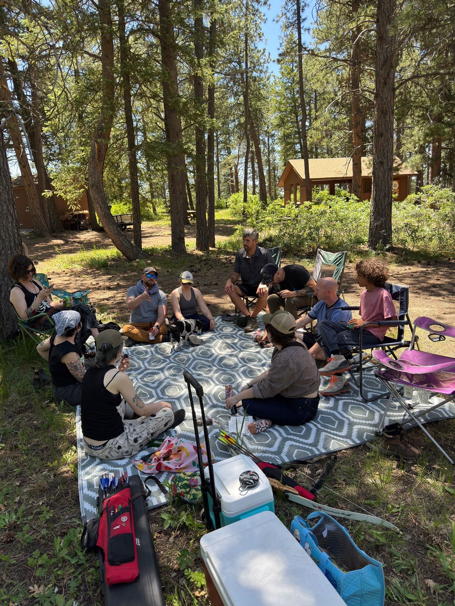 The group in conversation around a rug in the forest